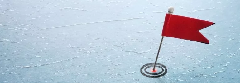 Small red flag on pin stuck into blue textured surface.