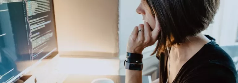 Femme concentrée sur un écran d'ordinateur affichant du code.