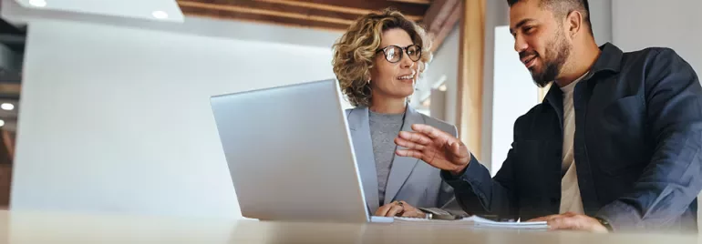 A woman and man talking in front of an open laptop