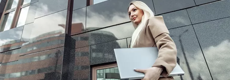 person walking with the laptop closed in the hand