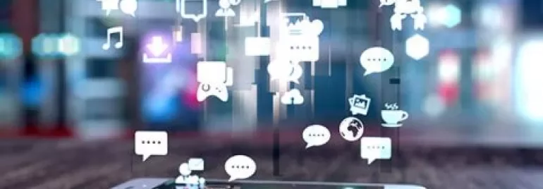 Smartphone with social media icons floating above it on a blurred background.