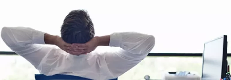 Homme se relâchant au bureau, regardant par la fenêtre.