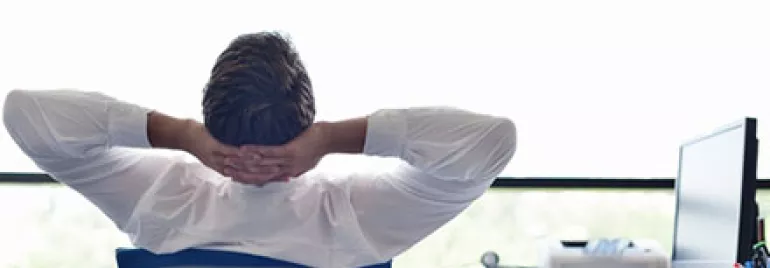Man relaxing at desk, looking out the window.
