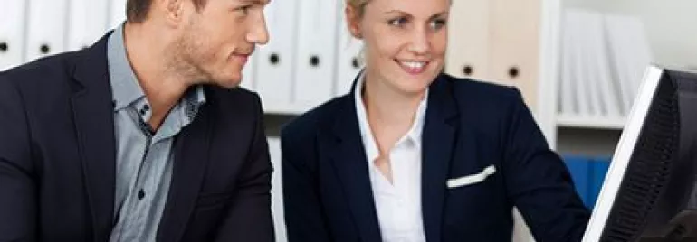 Deux professionnels discutent de quelque chose sur un écran d'ordinateur.