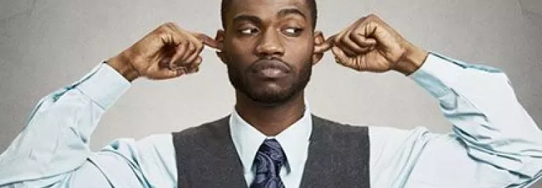 Homme portant un gilet et une cravate, se bouchant les oreilles.