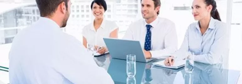 Réunion d'affaires dans un bureau moderne avec quatre personnes autour d'une table.