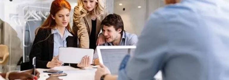 Quatre collègues collaborant autour d'une table avec des appareils technologiques.
