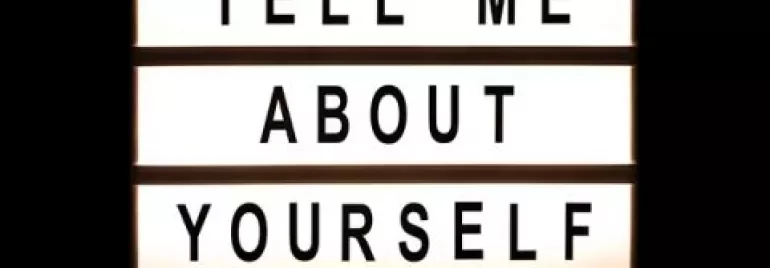 A lightbox sign displaying 'Tell me about yourself' in bold letters.