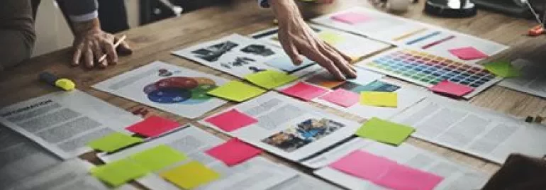 Réunion de brainstorming avec documents et post-its sur une table en bois.