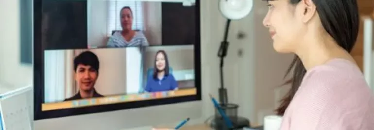 Woman participating in a video conference on a desktop computer.