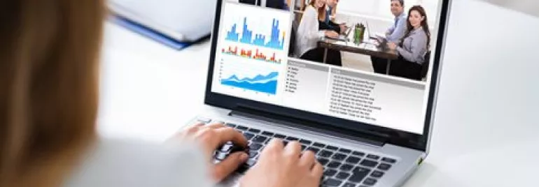 Person on video call with charts and graphs on laptop screen.