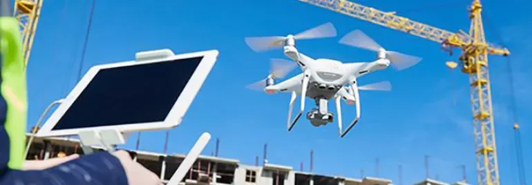 Drone flying near a construction site with cranes in the background.