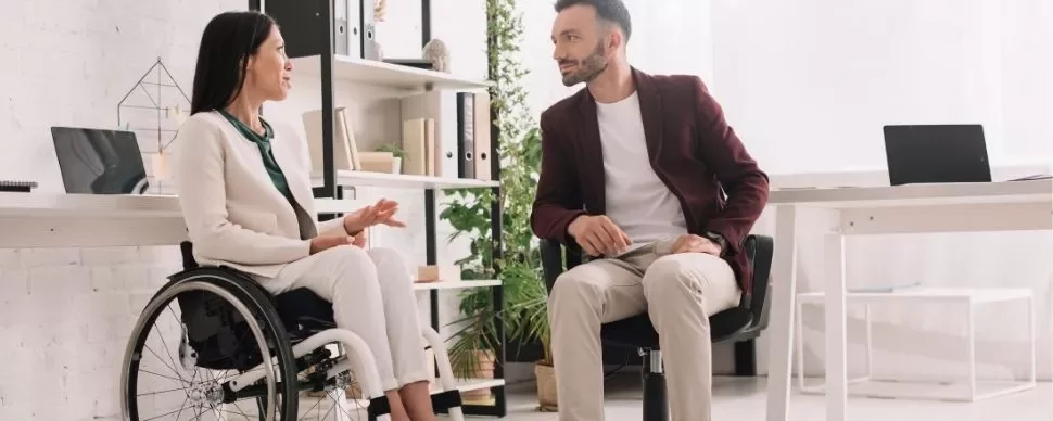 Deux collègues discutent dans un bureau moderne et lumineux.