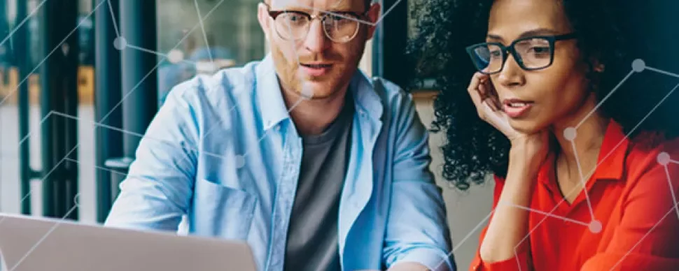 Two people collaborating on a laptop in an office.