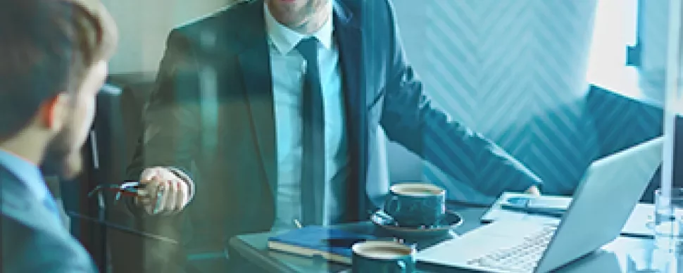 Deux hommes en réunion d'affaires avec un ordinateur portable et du café.