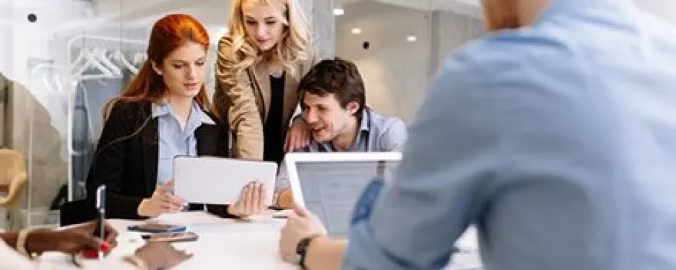 Quatre collègues collaborant autour d'une table avec des appareils technologiques.