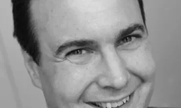 Black and white photo of a smiling man in a suit