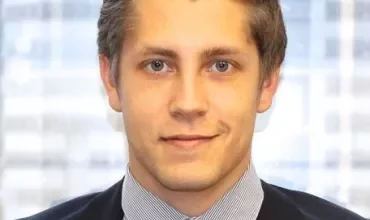 Young man in business attire with a cityscape background.