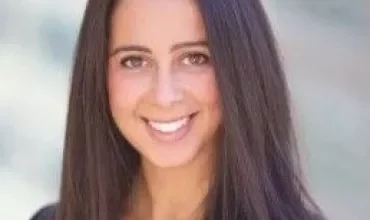 Portrait of a woman with long dark hair smiling at the camera.