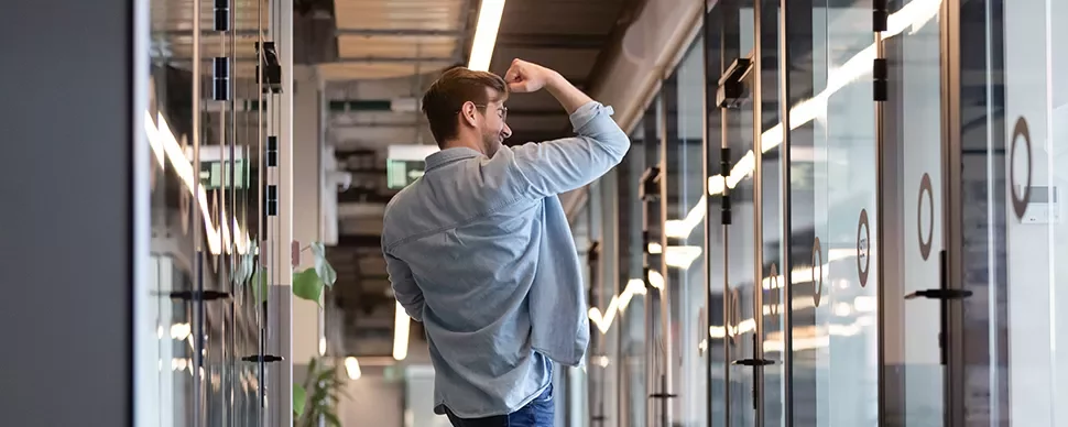 Man celebrating in modern office hallway.