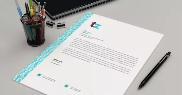 Mockup of a letter on a desk with pens and a notebook.