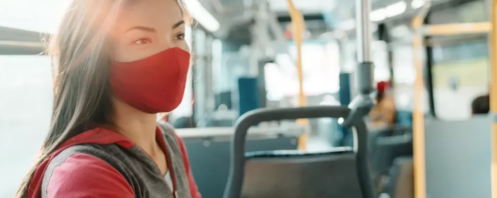 Woman wearing a red mask on a bus.