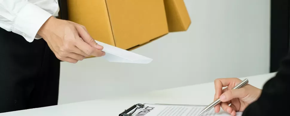 Person handing a document to another person signing a contract.
