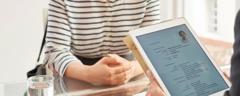 Person holding tablet with resume during interview.