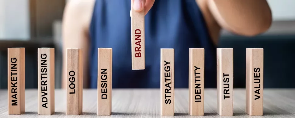 Hand picking wooden block labeled 'Brand' among others.