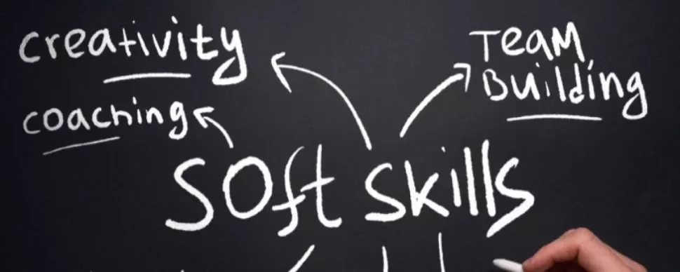 Hand writing 'soft skills' with words like creativity, coaching, and team building on a chalkboard.