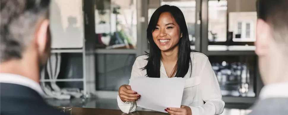 Woman smiling at a table during an office meeting.