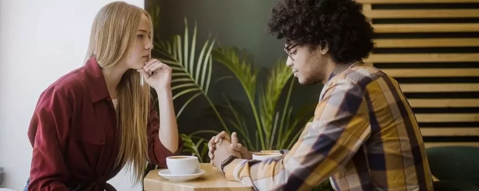 Two people having a serious conversation at a cafe table.