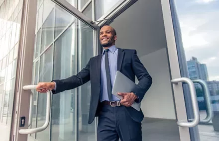 Businessman exiting office building with a laptop.