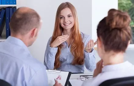 Smiling woman in a meeting with two colleagues, discussing a document.