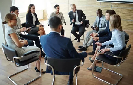 Group of people sitting in a circle having a meeting.