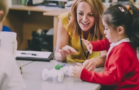 Teacher and child engaging in a fun learning activity with a toy