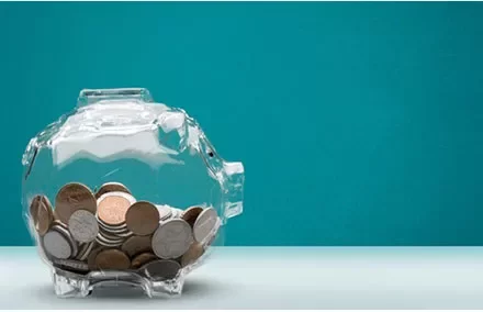 Transparent piggy bank filled with coins against a blue background.
