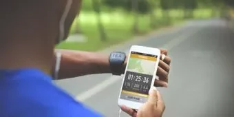 Person checking running app on smartphone during outdoor exercise.