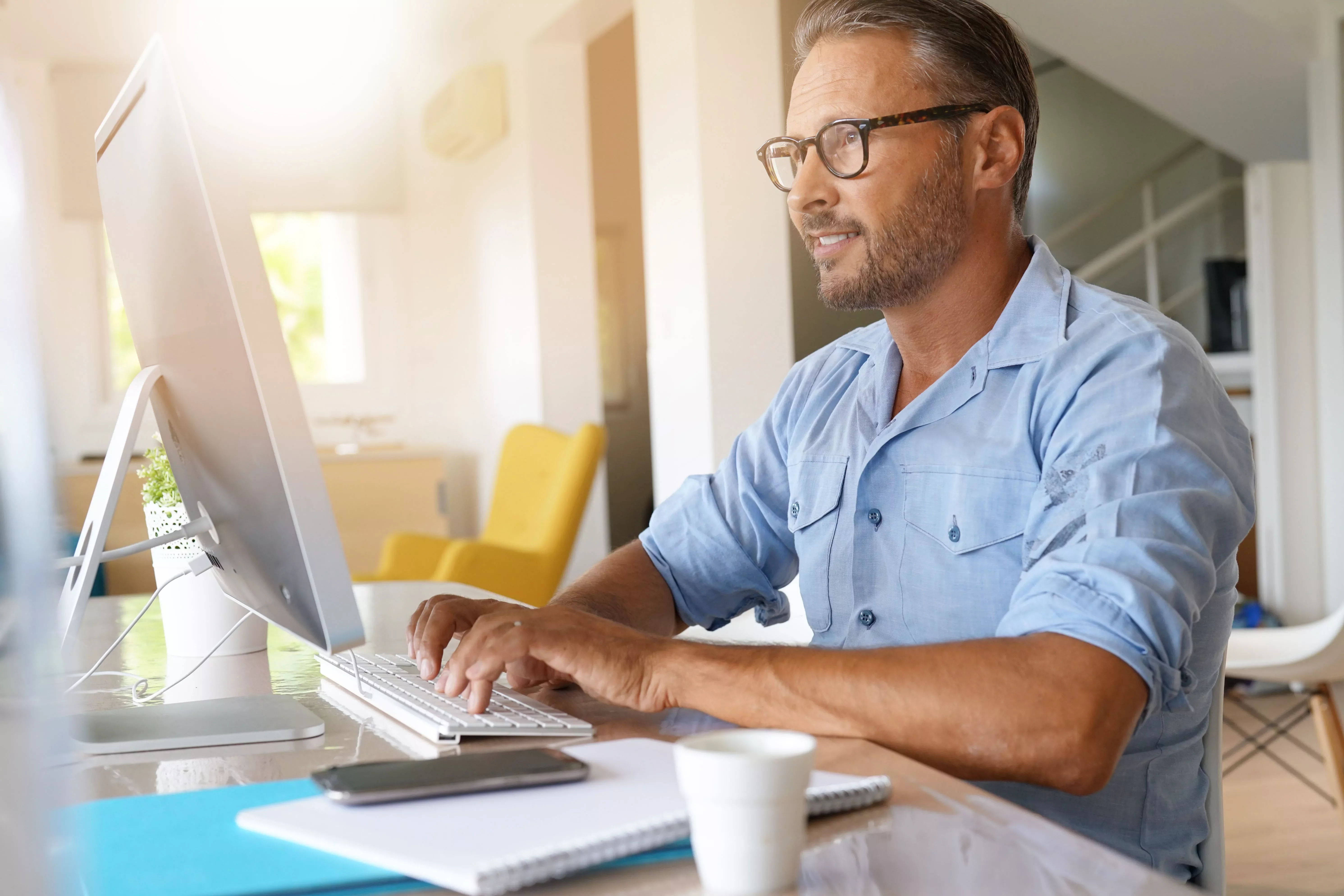 Man typing on computer in bright living room