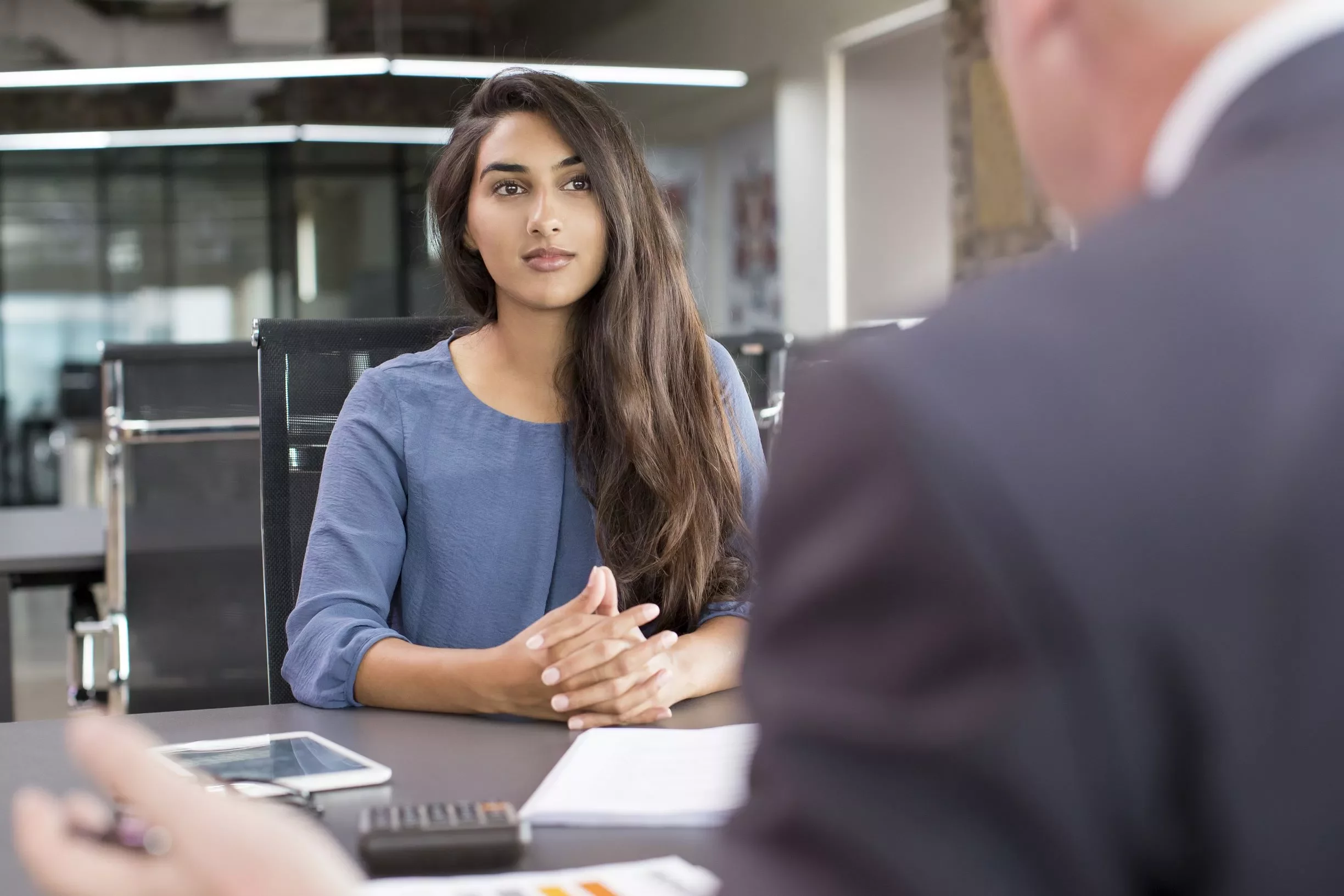 Woman in blue shirt at office meeting table.