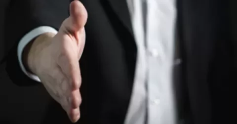 Close-up of a person reaching out for a handshake.