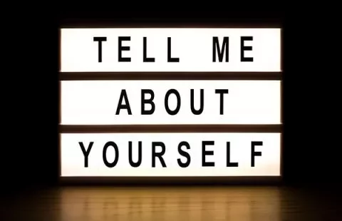 A lightbox sign displaying 'Tell me about yourself' in bold letters.