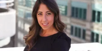 Woman smiling with city buildings in the background.