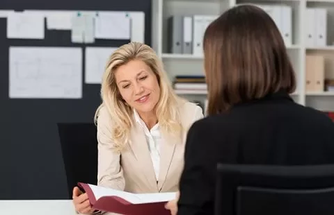 Two women having a discussion at a desk in an office.