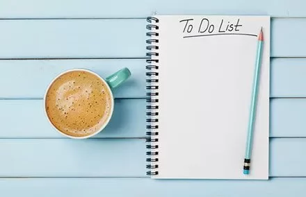Notepad with 'To Do List' beside a coffee on a blue table.