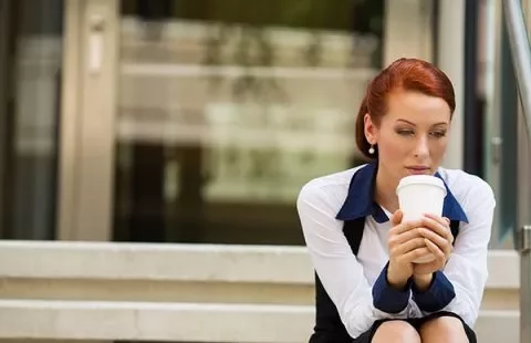 Woman sitting on steps holding a coffee cup.