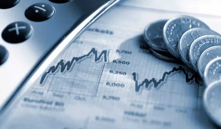 Calculator and coins on a financial graph.